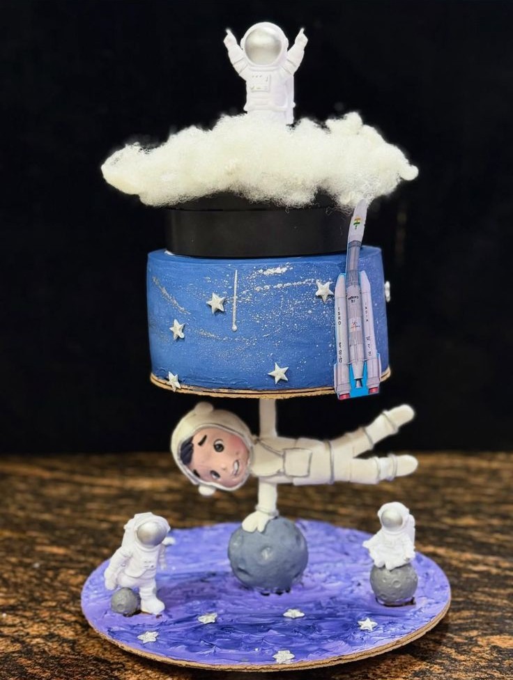 Astronaut themed custom cake with moon surface base and space decorations